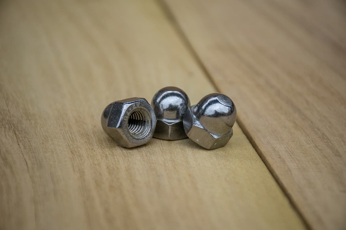 Three lug nuts on a wooden table.