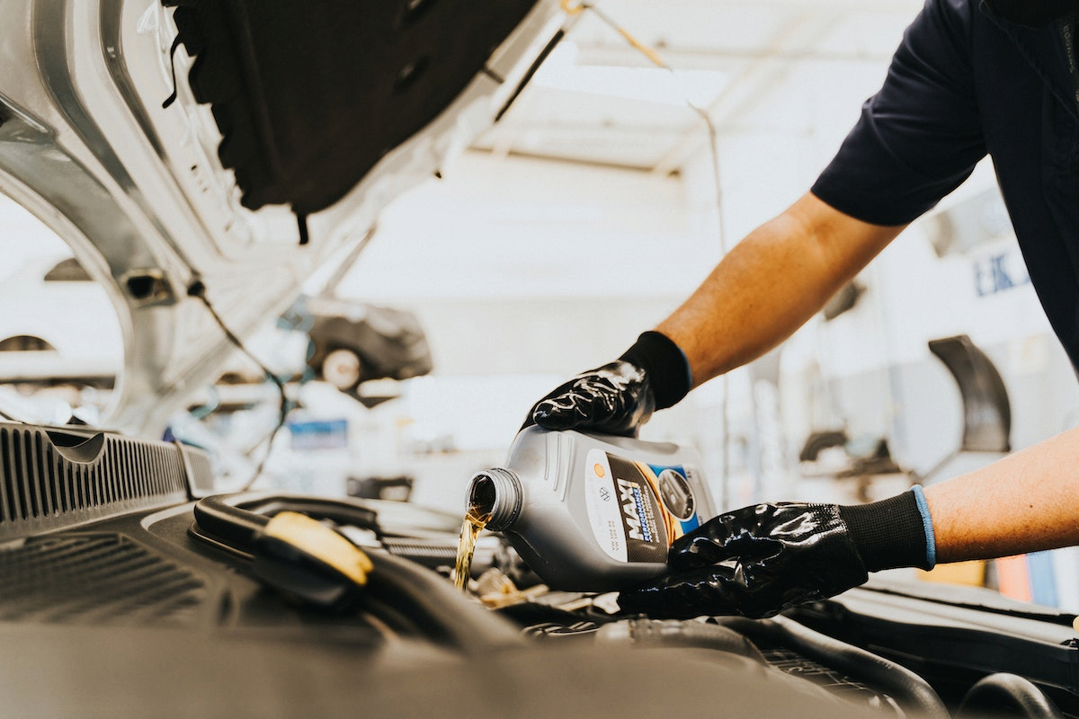 a man pouring oil to his car's engine