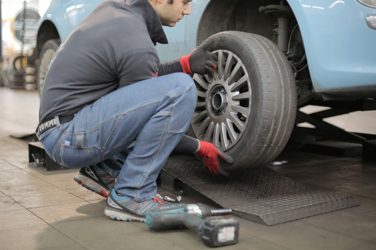 a man in a black sleeve shirt is changing the tire of a car