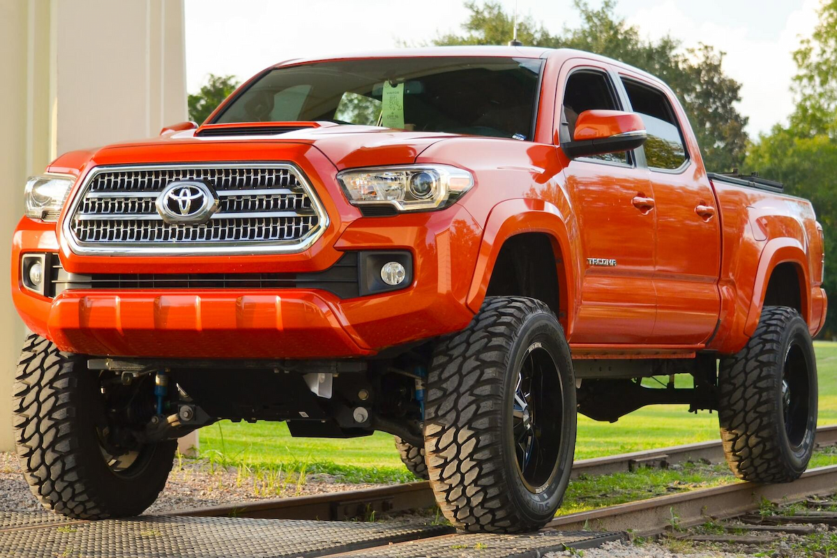 a red Toyota Tacoma is seen parked in the middle of a road