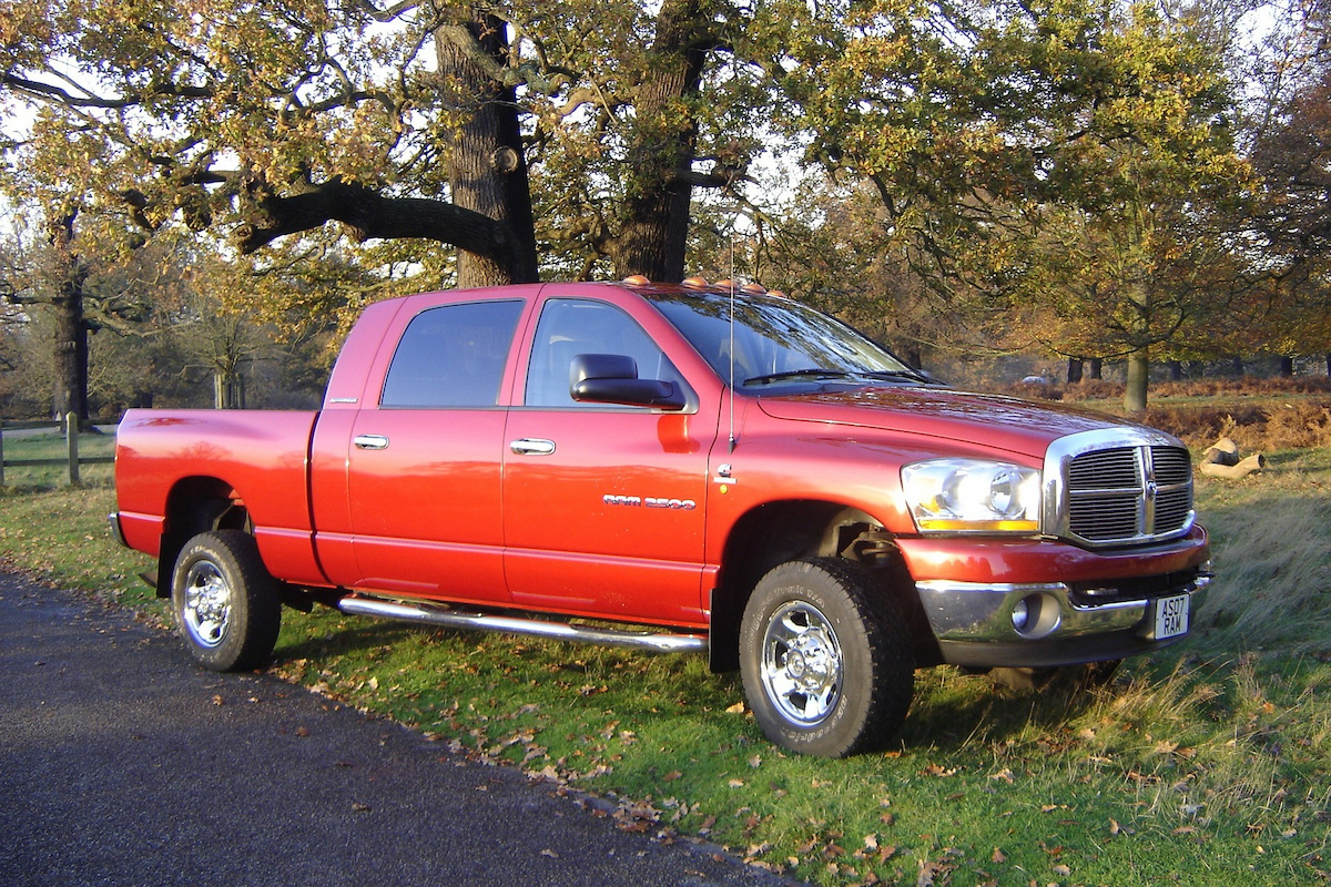 a reddish dodge ram in the forest near the road