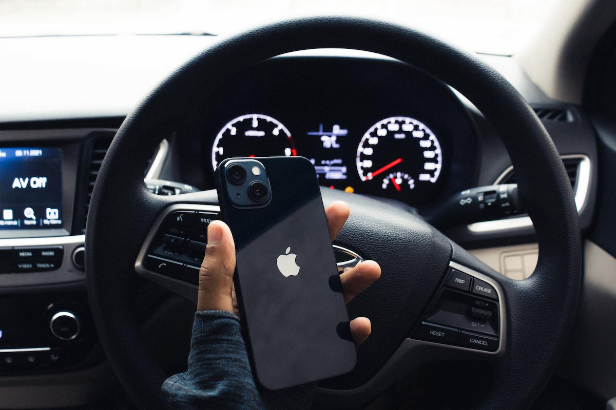 a steering wheel of a car with someone holding an iphone