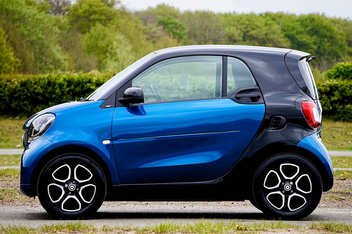 A blue electric car is parked on a road with grass.