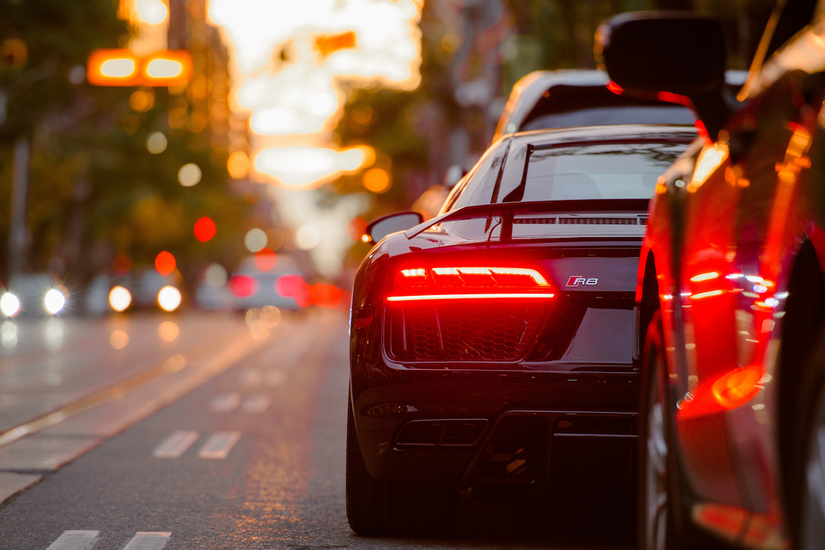 A vehicle tailgating a black car with its tail light turned on.