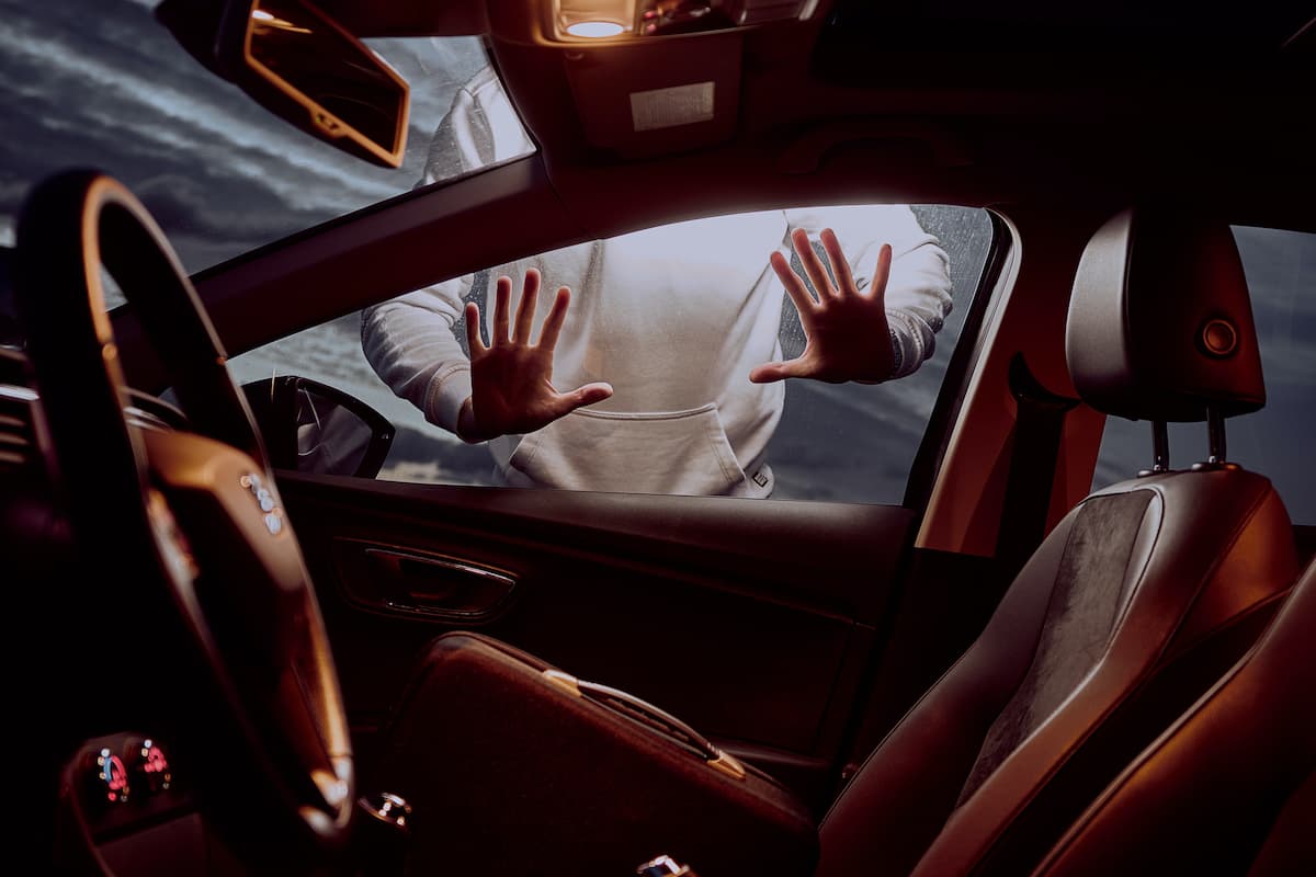 A photo of a man's hands on the window of a car. 