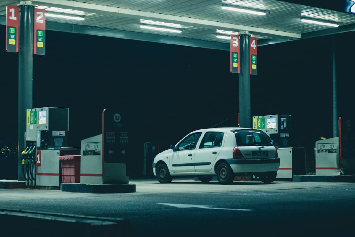 A white car in a gas station at nigh time.  