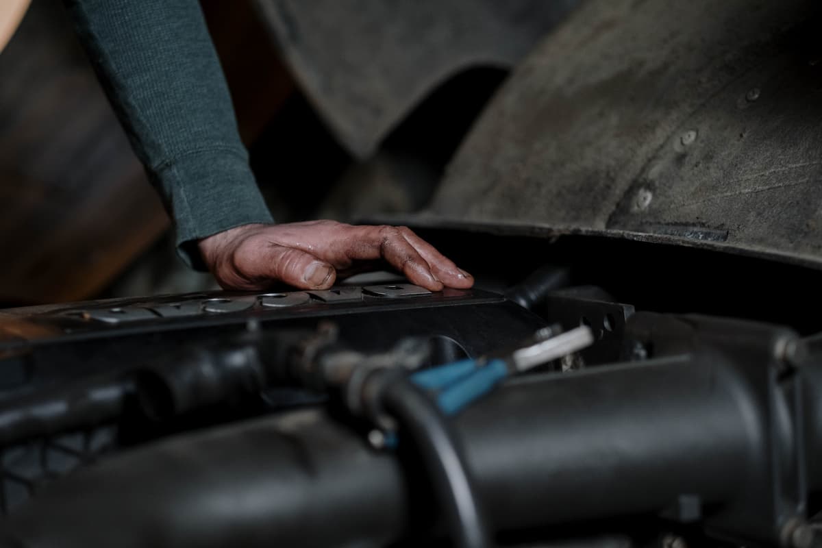 A mechanic with a greasy hand checking a car's engine.