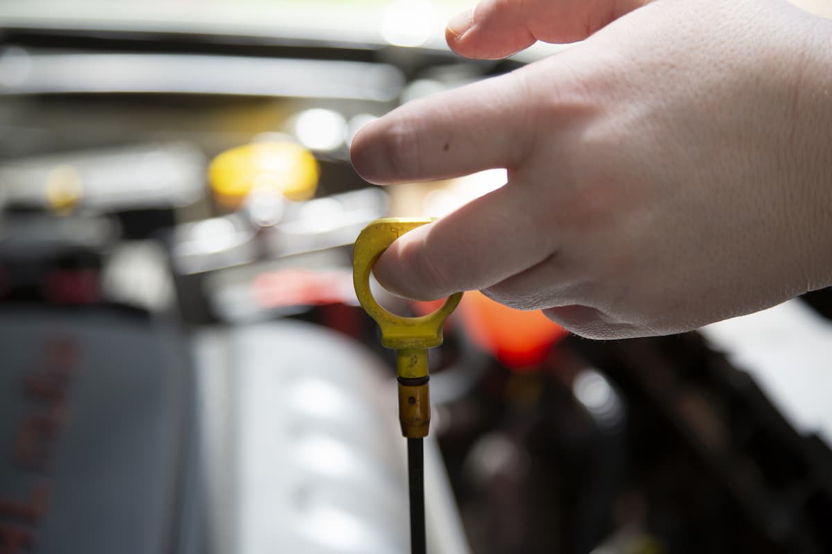 Close-up photo of a woman's hand checking the transmission fluid in a car. 