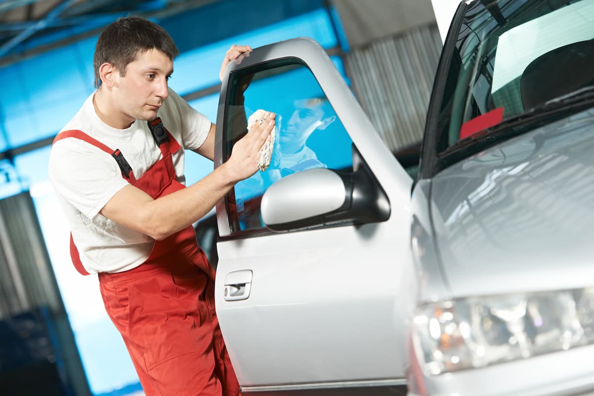 A mechanic is cleaning the car's door.