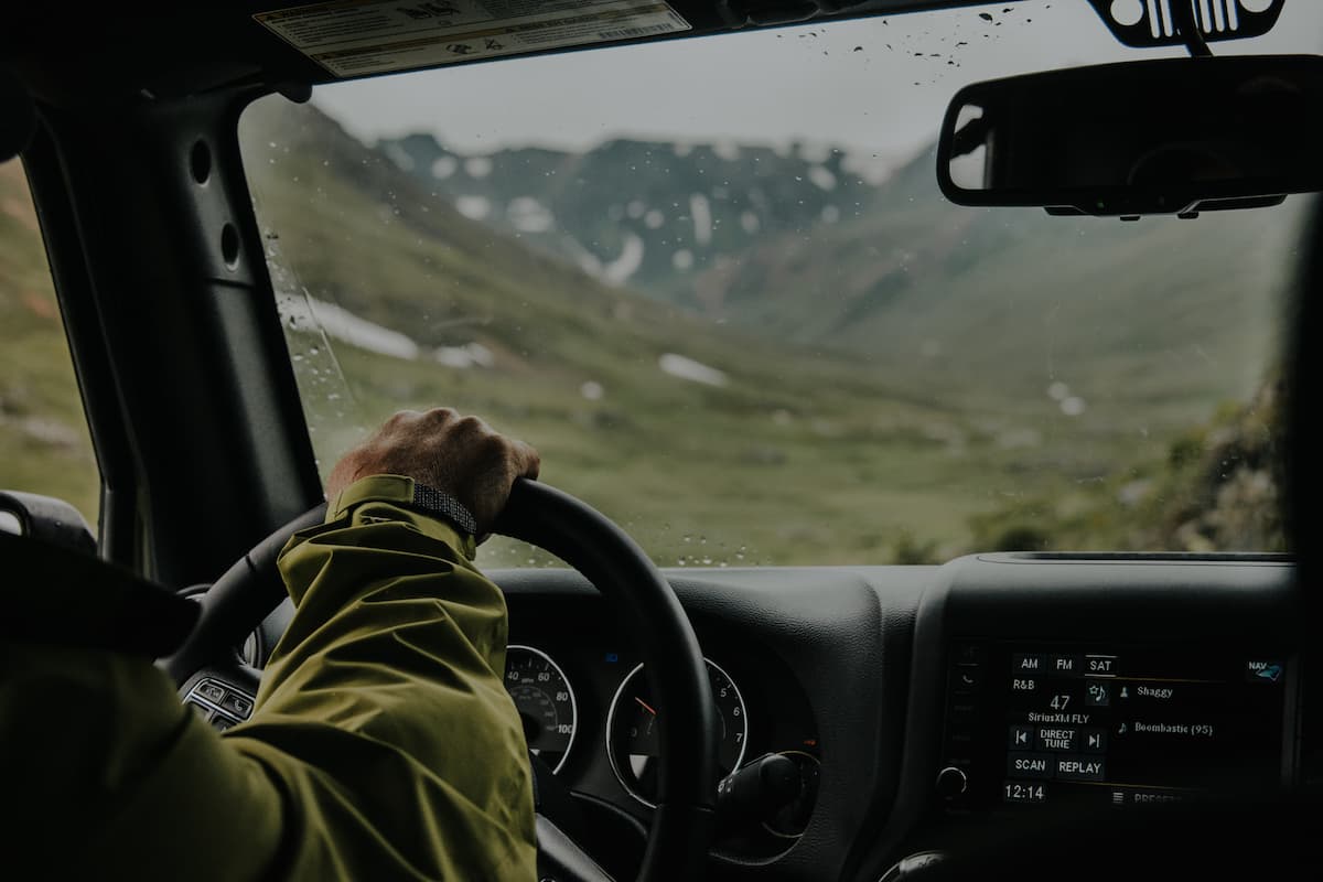 A man wearing a green jacket driving in the mountains. 