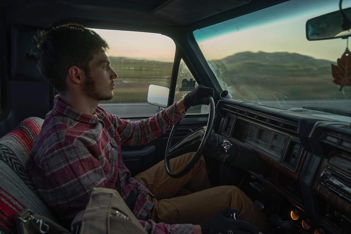 A man in red plaid shirt driving a truck.