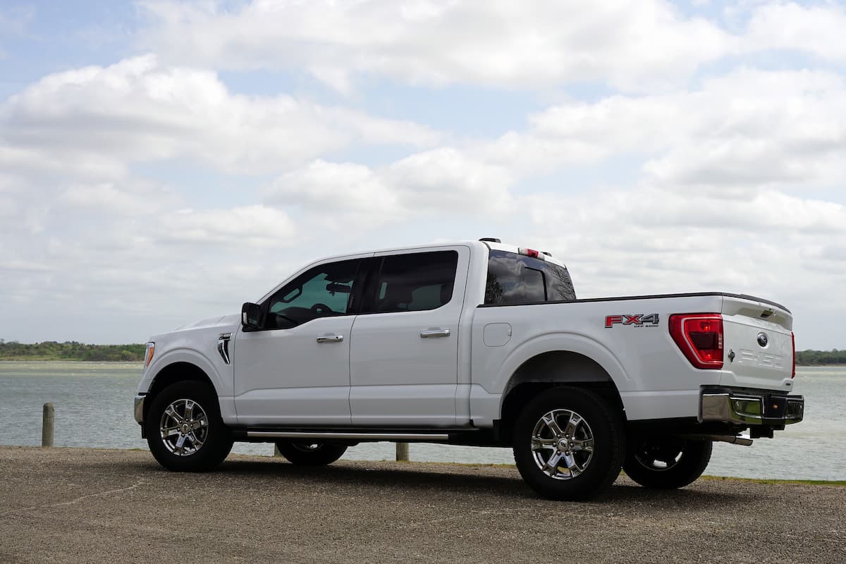 A white Ford F-150 parked near the sea. 
