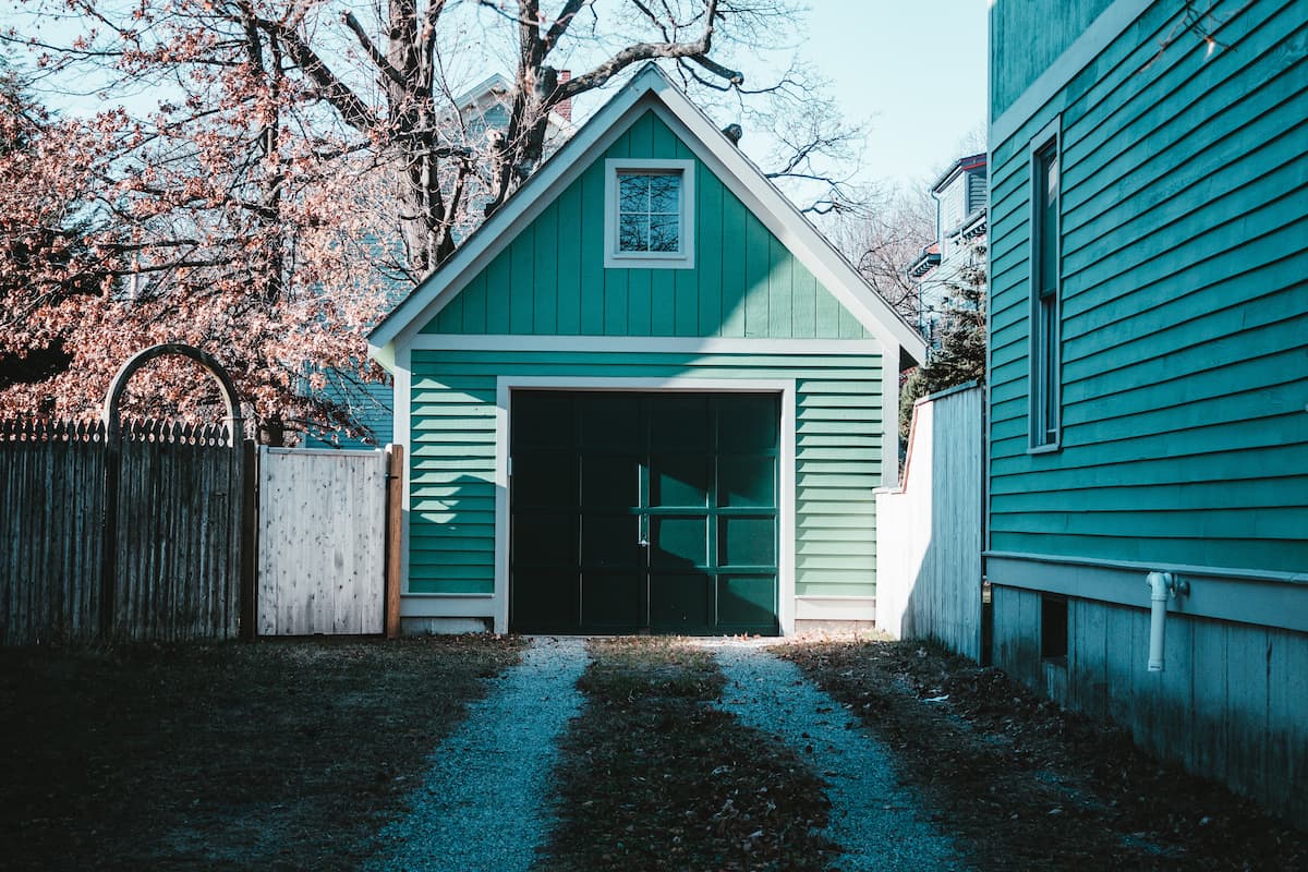 The garage of a blue and white wooden house. 