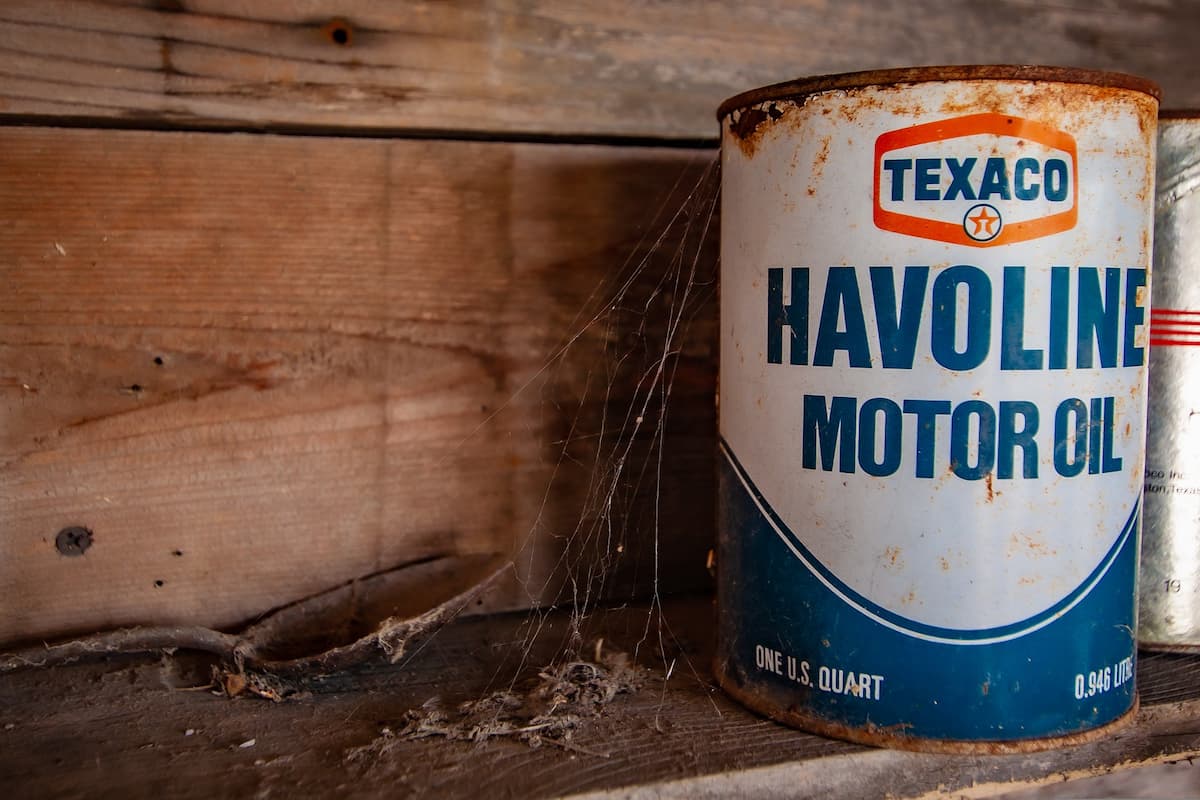 An old Havoline Motor Oil is stored on a webbed shelf. 