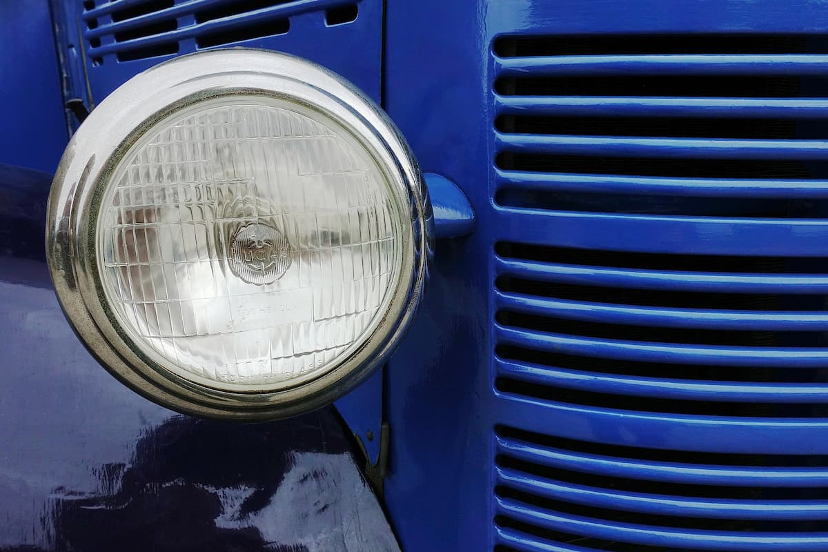 A close-up photo of a headlight of a blue vehicle. 