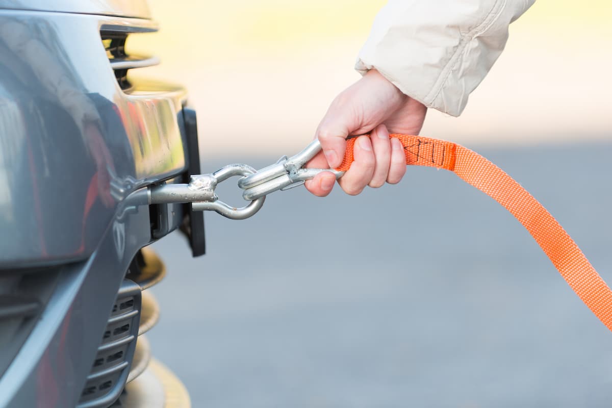 A woman's hand holding a tow rope attached to a car. 