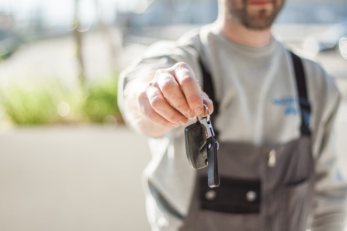 A blurred man in an apron showing a car's key. 