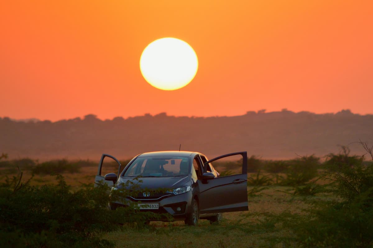 A Honda Fit parked with its doors open during sunset. 