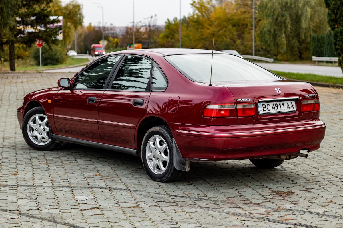 Side view photo of red Honda Accord parked in a parking lot. 