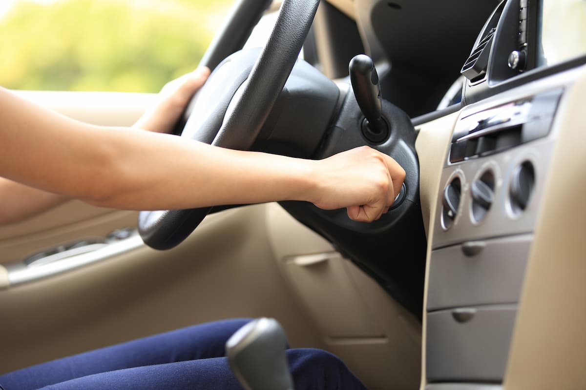 A woman's hand starts the car with a car key. 