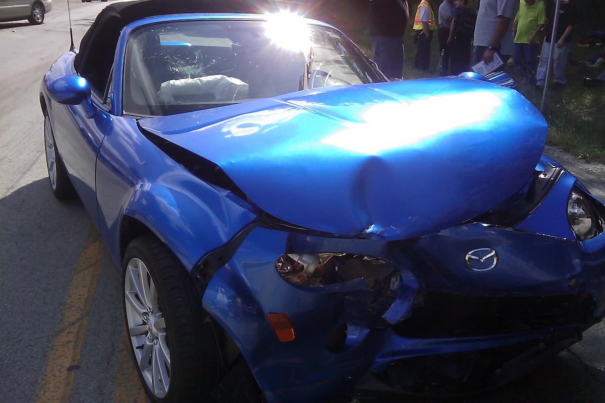 A blue totaled car on a road.