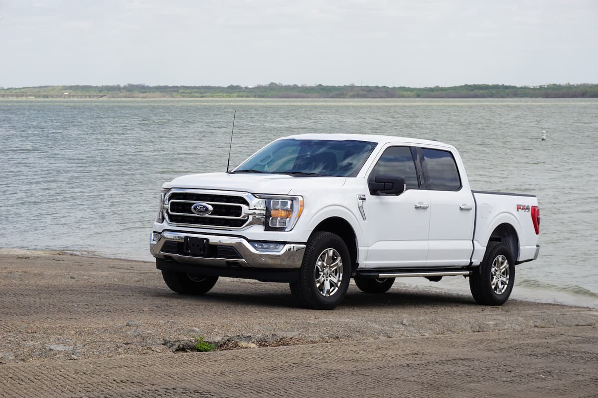A white Ford pickup truck parked near the beach.